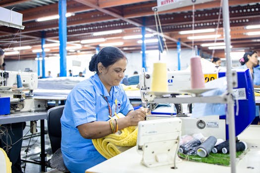Indian woman working efficiently in a textile factory, sewing fabrics.